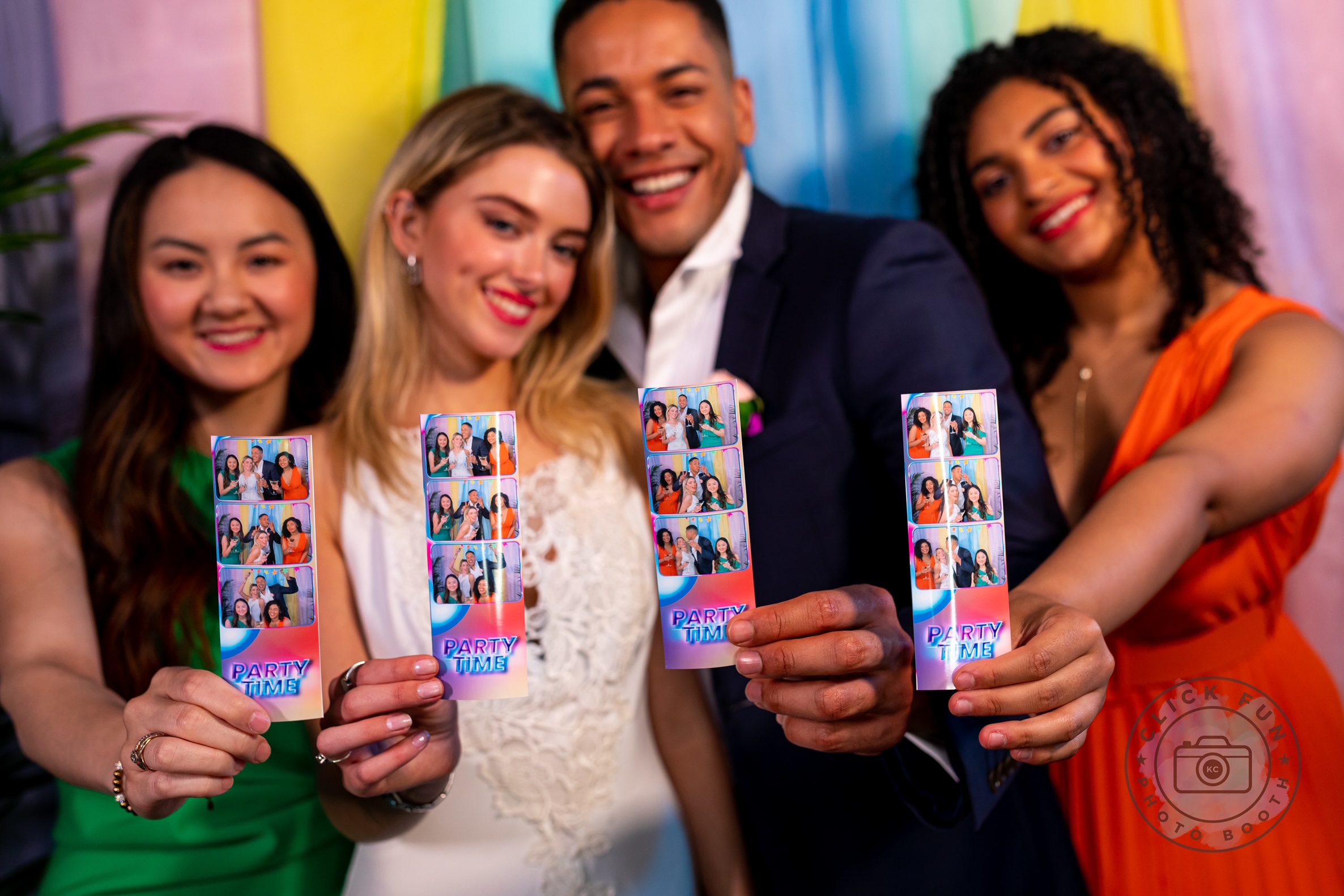 Group of people holding up printed photo booth strips at a wedding