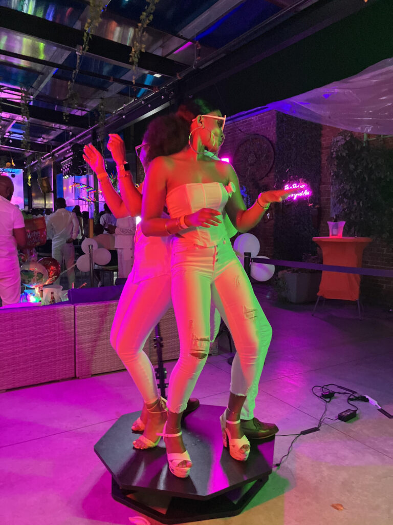 Person posing on a 360 photo booth platform with pink lighting