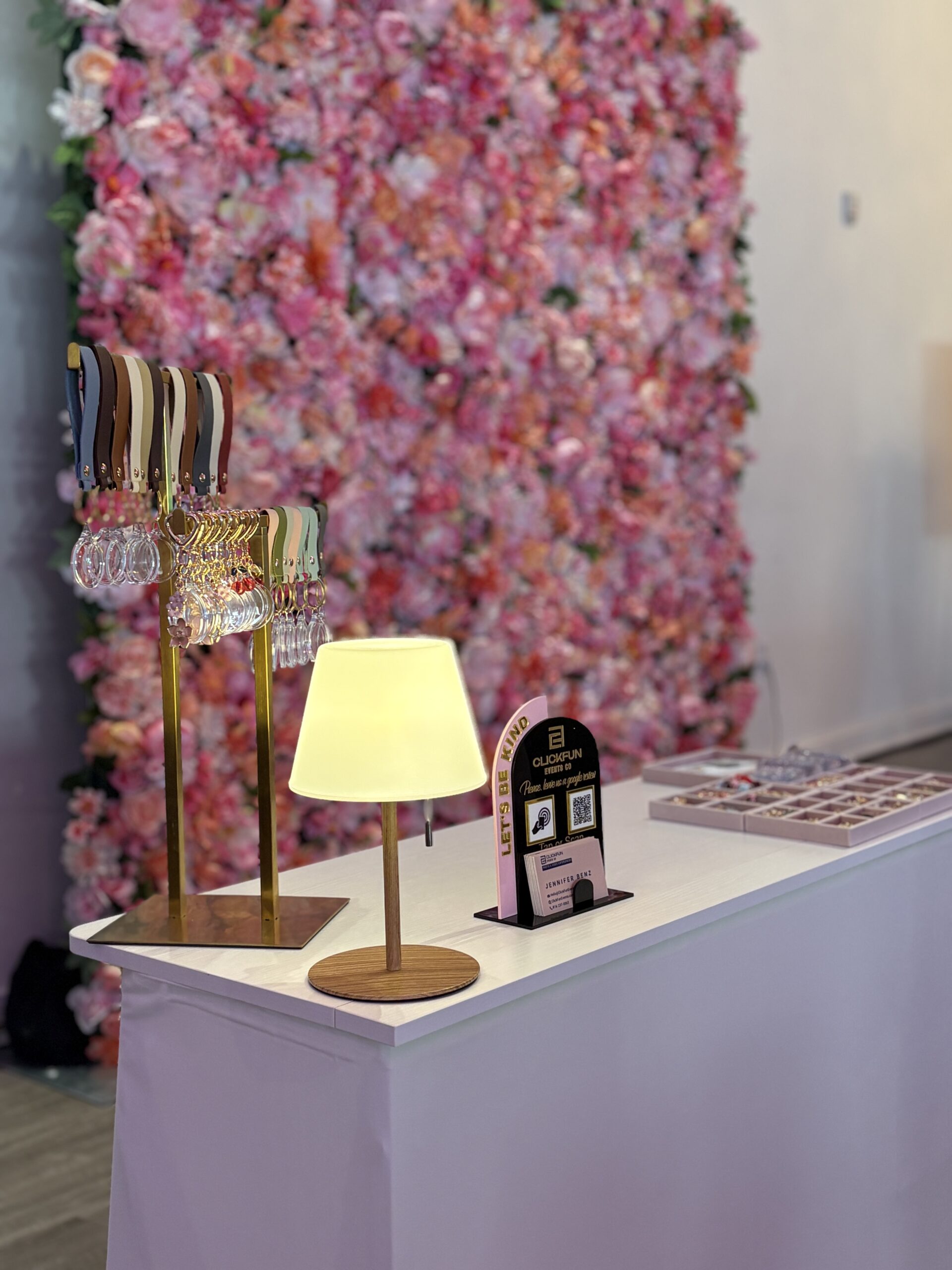 Pink floral photo booth backdrop with a lamp and table setup