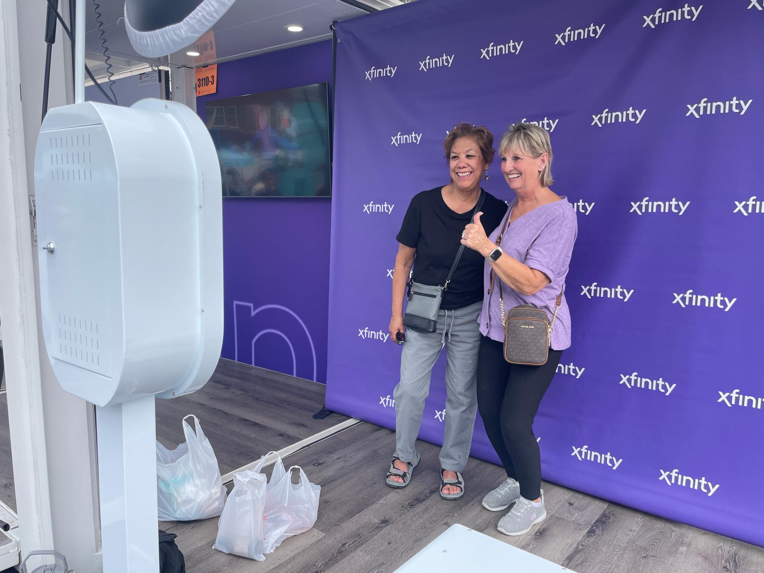 Two people posing together in front of a purple branded photo booth