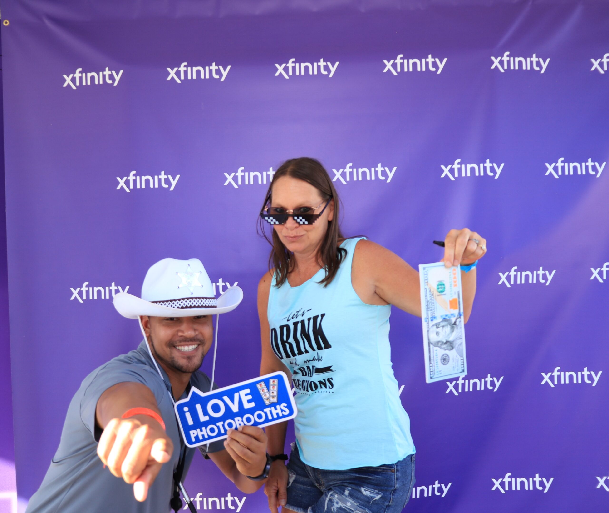People posing together in front of a dark branded background, one wearing a cowboy hat