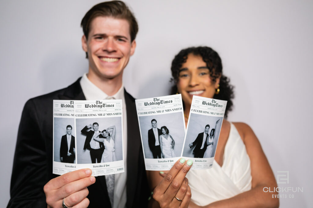Man and woman holding up a printed wedding photo card, smiling