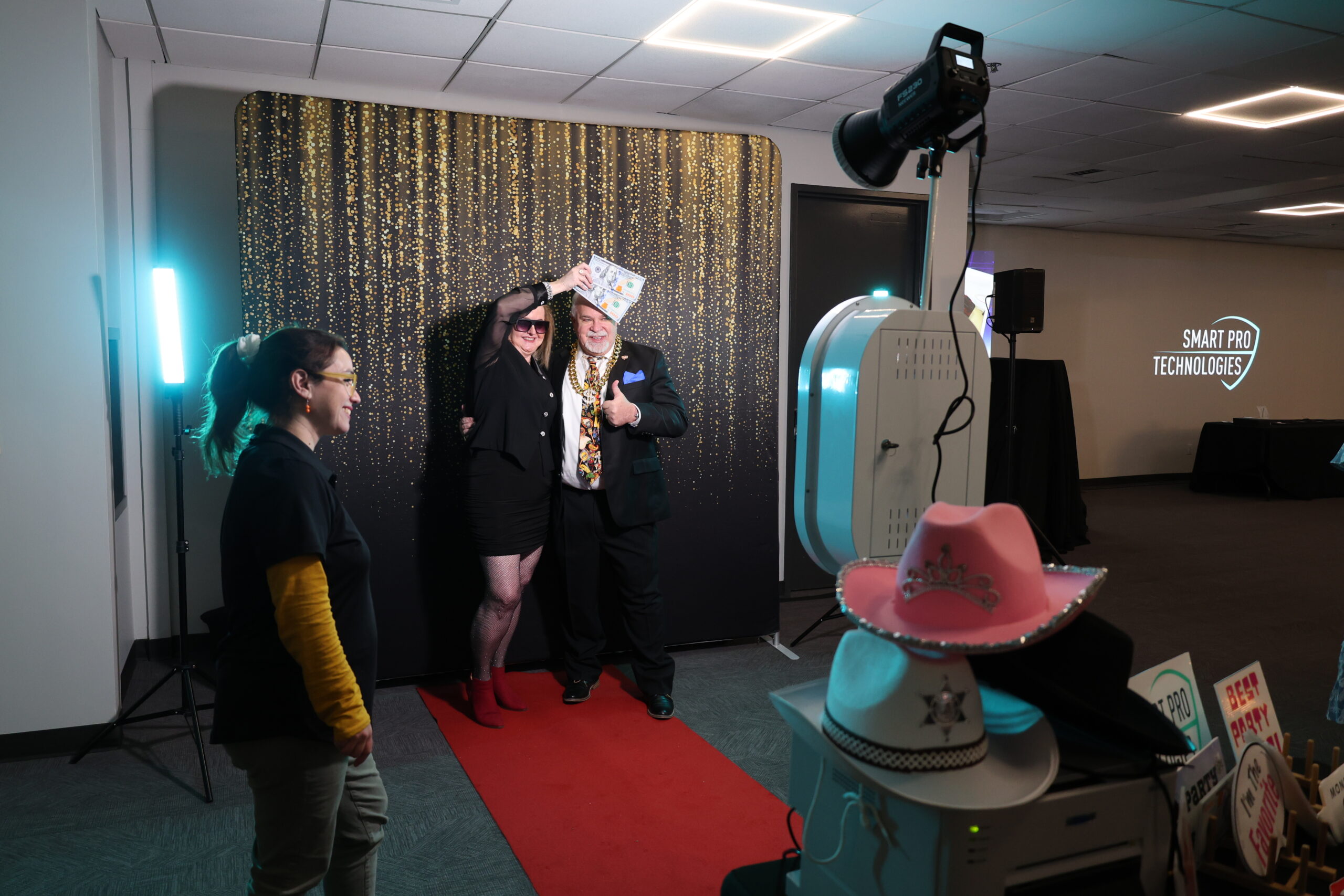 People posing at a photo booth with a red curtain backdrop