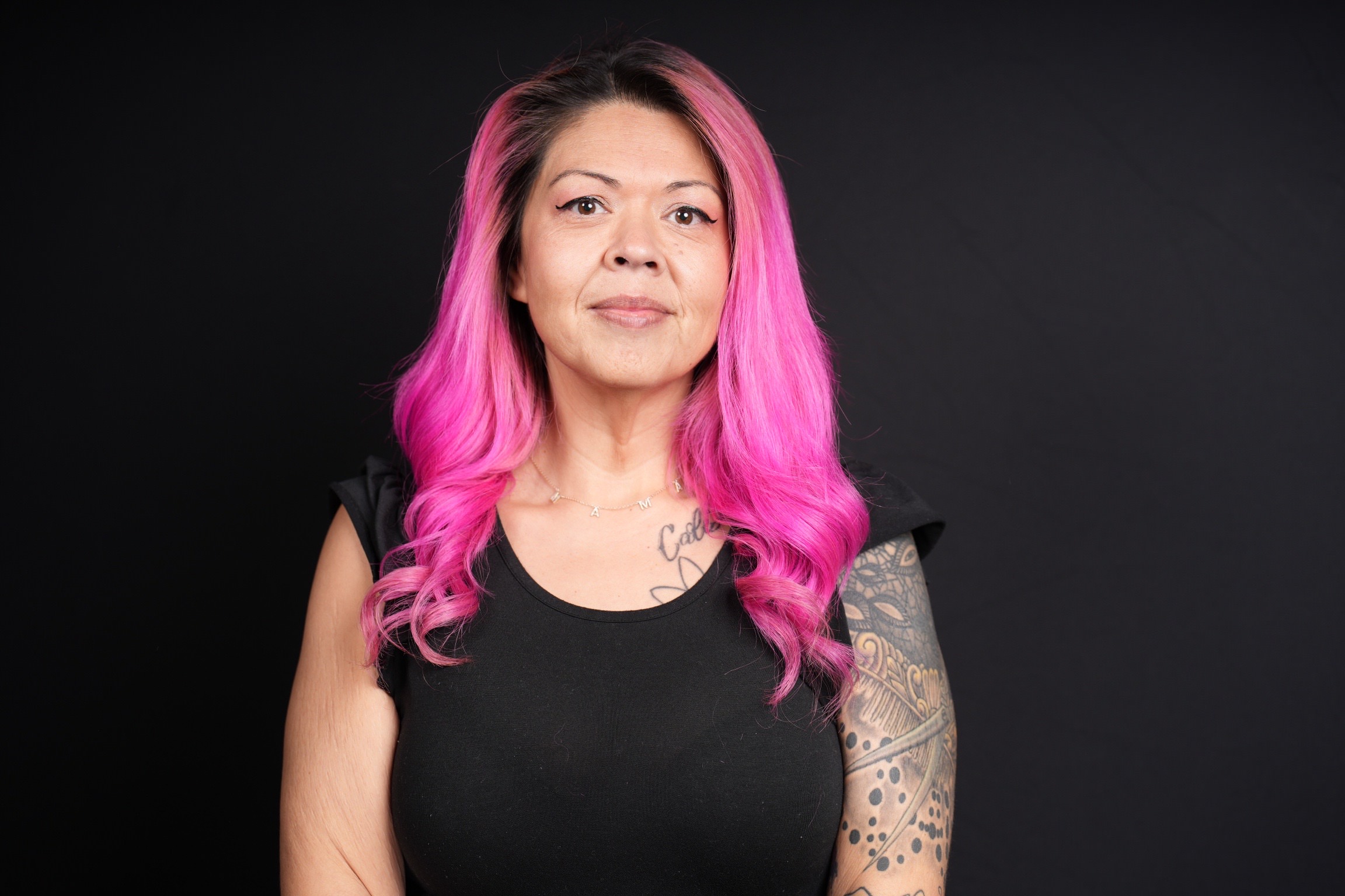 Woman with pink hair smiling for a headshot