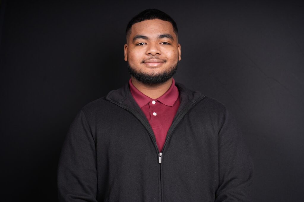 Man in a black jacket smiling for a headshot