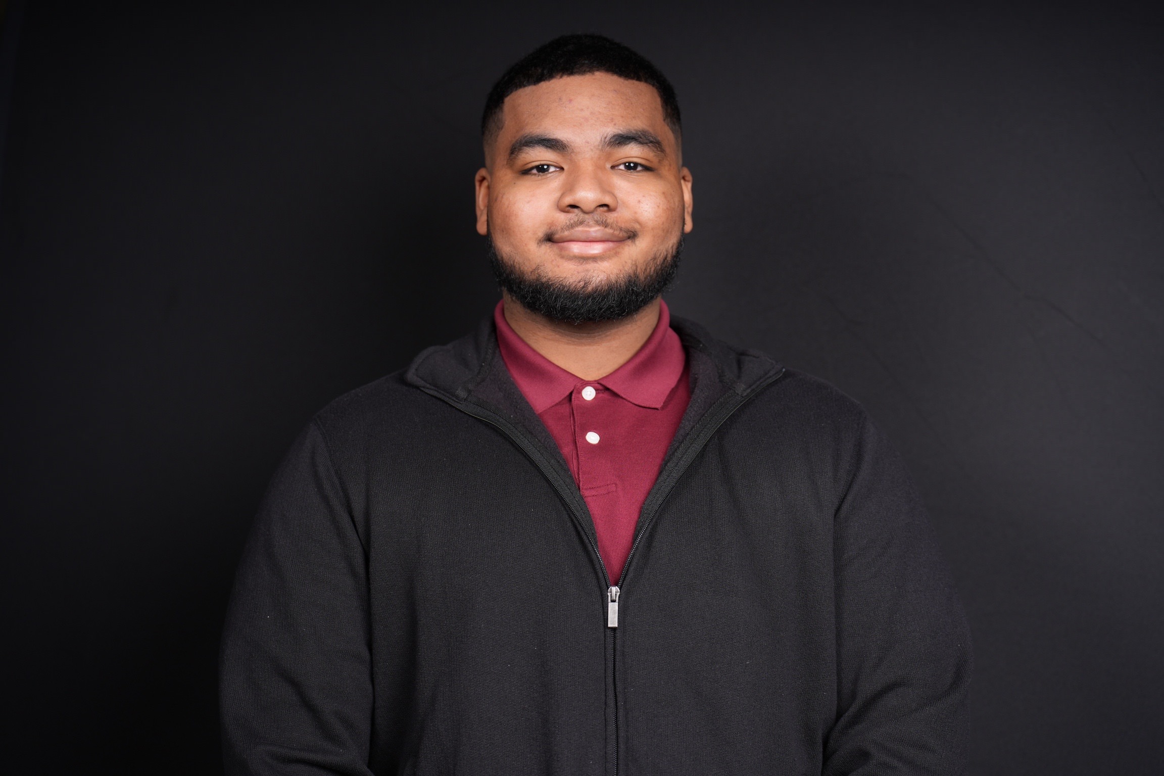 Man in a black jacket smiling for a headshot